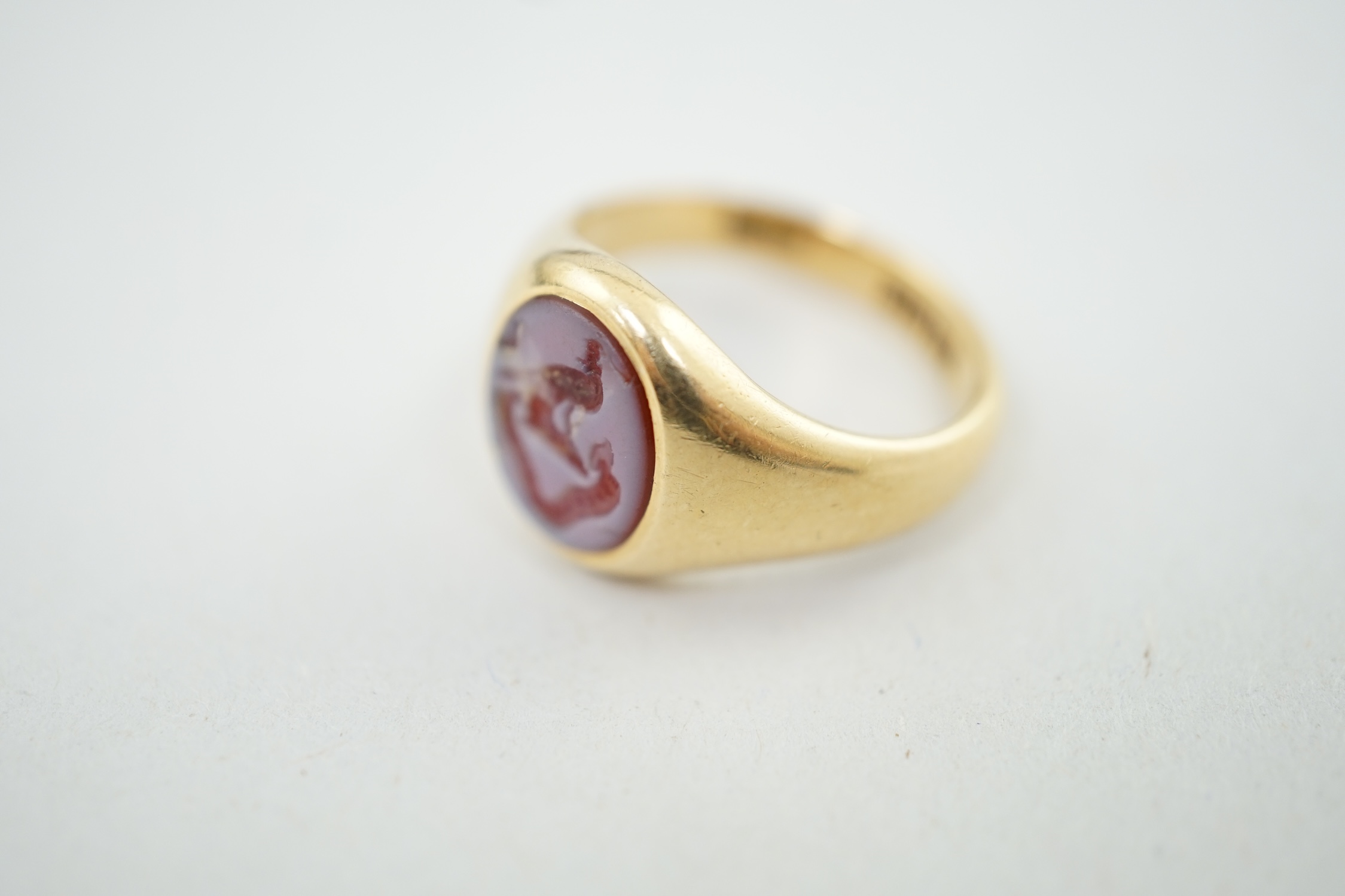 A George V 18ct gold and sardonyx set signet ring, the oval stone carved with family crest